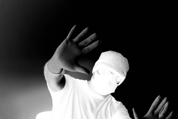 Ritratto di uomo protetto dal coronavirus. Guanti bianchi in lattice. Protezione delle mani contro infezioni, virus, germi. Isolamento della pelle. Sul viso è una maschera di tessuto. Occhiali sugli occhi
.  - Foto, immagini