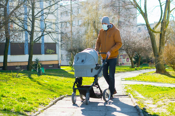 Man o a walk with baby in baby carriage during coronavirus  - Foto, afbeelding