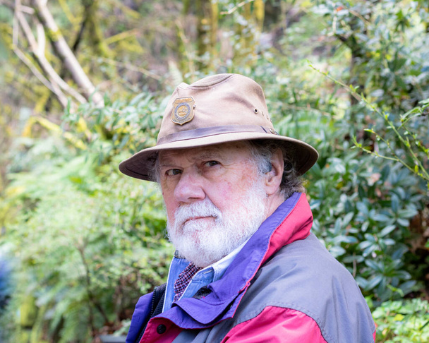 Серйозна розсудлива кормова бородата старший здоровий чоловік в коричневому капелюсі і піджаку, зовні, дивлячись в камеру
 - Фото, зображення