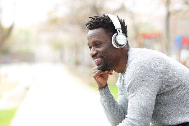 Happy black man listening to music with headphones - Zdjęcie, obraz