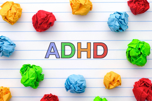 ADHD. Abbreviation ADHD on notebook sheet with some colorful crumpled paper balls around it. Close up. ADHD is Attention deficit hyperactivity disorder. - Foto, Bild