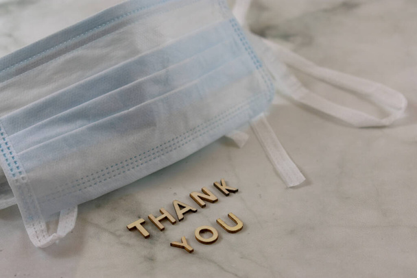 Surgical mask with thank you sign over marbled background with copy space - Photo, Image