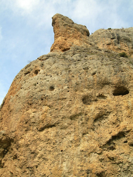 Ένας μεγάλος καφέ βράχος γεμάτος τρύπες. Μπλε ουρανός, προοπτική - Φωτογραφία, εικόνα