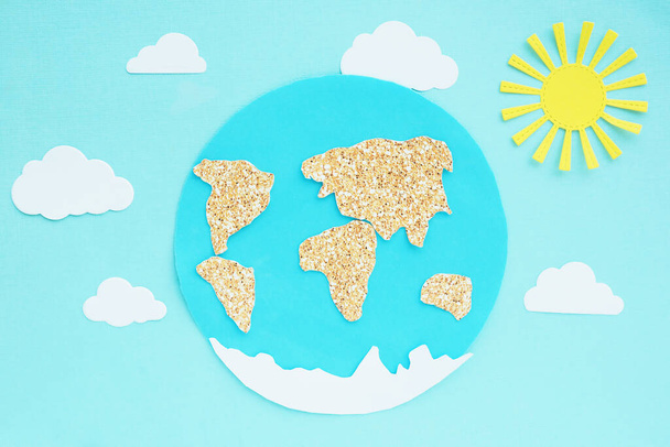 paperisovellus: planeetta Maa, maanosat, pilvet ja aurinko sinisellä pohjalla
 - Valokuva, kuva