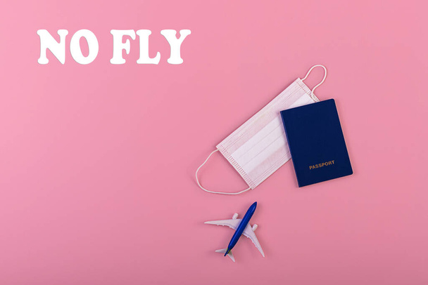 Surgical mask, plane and passport on pink background. Virus protection equipment. Dangerous asian ncov coronavirus. Concept of fly danger - Photo, Image
