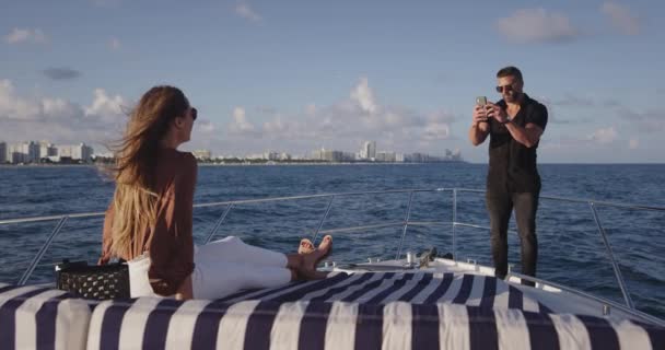 Man taking photo of girlfriend on boat in ocean - Záběry, video