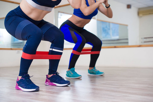 Sportmeisjes sporten met elastiekjes in de sportschool in lichte tinten. - Foto, afbeelding