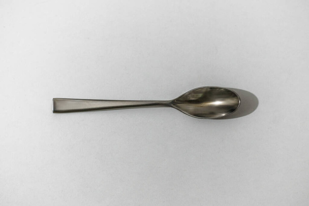 Beautiful view of a metal small spoon on a white and light background - Foto, imagen