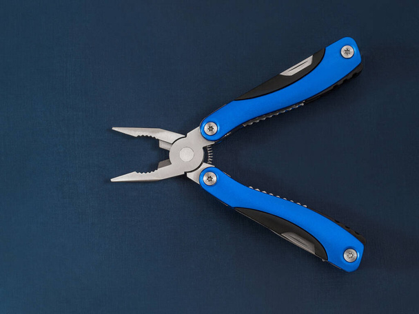 A beautiful folding knife, a mobile male tool and an accessory with several tools for work and repair on a dark blue background. - Fotó, kép