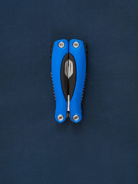 A beautiful folding knife, a mobile male tool and an accessory with several tools for work and repair on a dark blue background. - Fotografie, Obrázek