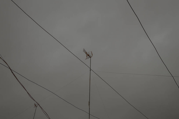 Dark winter day with storm causes interference and the TV signal fails. Stormy and cloudy background with television antennas and cables. - Photo, Image