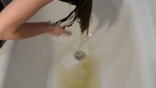 A young woman washes hair dye in the bathroom after dyeing hair - Video, Çekim