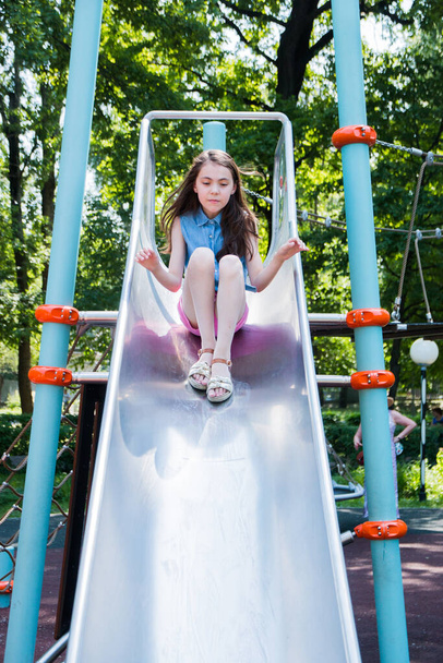 portrait of girl playing on playground in park in summer time. summer vacation. - Фото, изображение