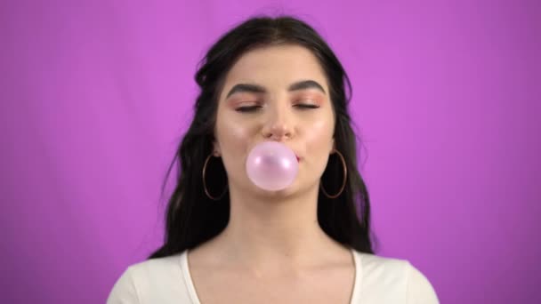 Brunetka dziewczyna dmuchanie różowy guma balonowa na zielony ekran - Materiał filmowy, wideo