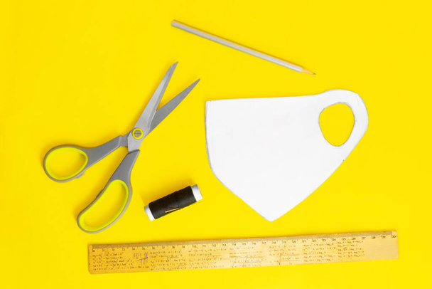 Создание медицинской маски для лица дома с швейным набором, черная маска на желтом фоне, компоновка объектов
 - Фото, изображение