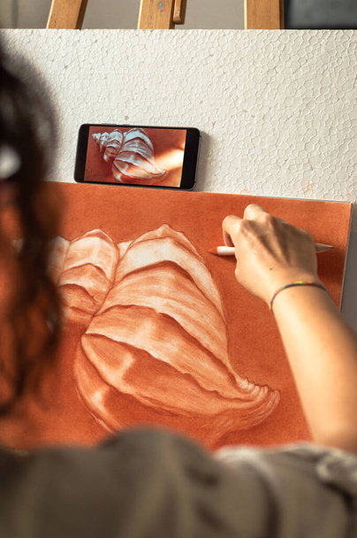 Žena, která používá fotografii mobilního telefonu, odkazuje na kreslení obrazu doma před jasným oknem. Využití technologie k malování. - Fotografie, Obrázek