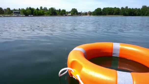 Πορτοκαλί σημαδούρα διάσωσης ζωής επιπλέει σε νερό λίμνης μακριά από την ακτή. Λαμπερή κίνηση - Πλάνα, βίντεο