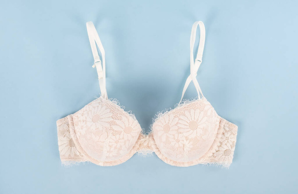 Light Pink Lace Bra with Floral Pattern on Baby Blue Background - Photo, Image