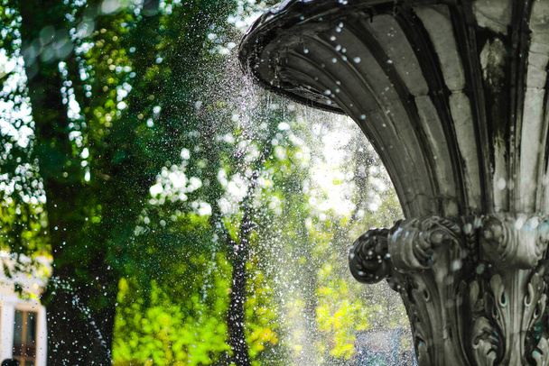fontein in de stad. waterdruppels. spetterend uit een fontein op een achtergrond van de zonnige hemel. Stadsarchitectuur. - Foto, afbeelding