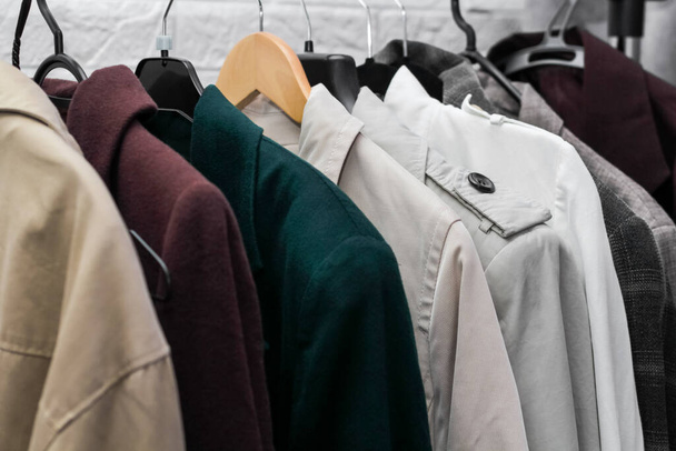 kleren aan een hanger. Macro. nieuwe collectie kleding. jassen, regenjassen en jasjes. - Foto, afbeelding