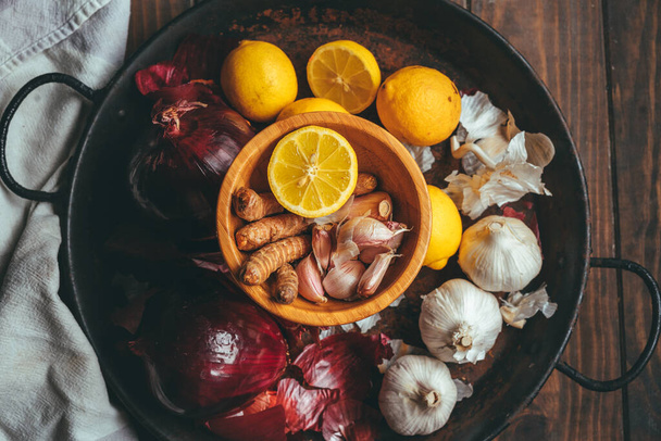 Paella with onion, turmeric, garlic and lemon on a wooden table in a rustic tone - Photo, image