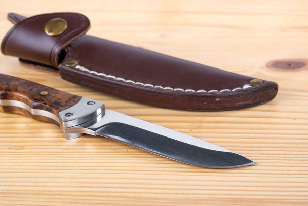 Hermoso cuchillo de caza y funda en la mesa de madera, objeto
 - Foto, imagen