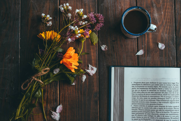 Kırsal bir masa üzerinde küçük beyaz bir fincan kahveyle bahar çiçekleri olan bir kitap. - Fotoğraf, Görsel