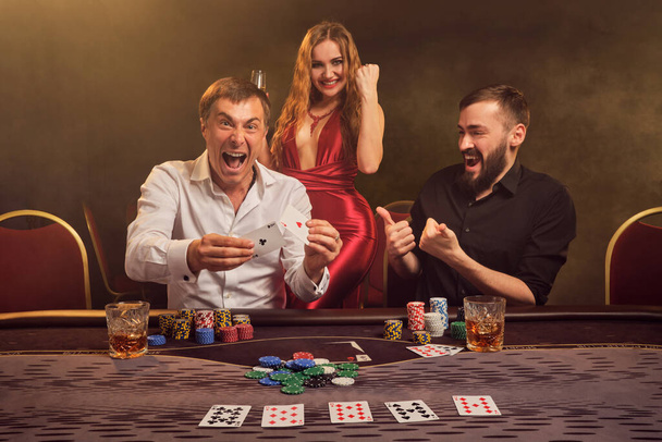 Grupa młodych zamożnych przyjaciół gra w pokera w kasynie. - Zdjęcie, obraz