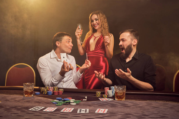 Group of a young wealthy friends are playing poker at a casino. - Photo, Image