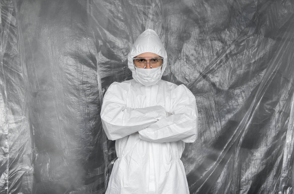 Doctor in white protective suit, mask, glasses and rubber gloves is ready for helping a people while coronavirus pandemic threat. Epidemic, pandemic of coronavirus covid 19. Doctor in respirator. - Фото, изображение