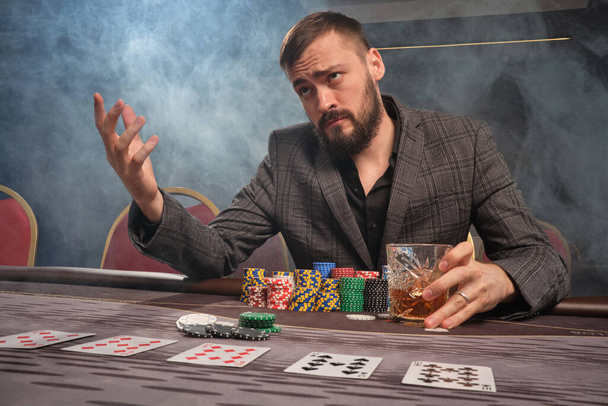 Hezký vousatý muž hraje poker sedí u stolu v kasinu. - Fotografie, Obrázek