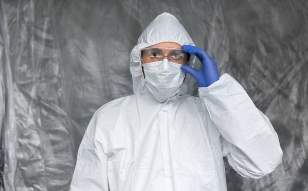 Doctor in white protective suit, mask, glasses and rubber gloves is ready for helping a people while coronavirus pandemic threat. Epidemic, pandemic of coronavirus covid 19. Doctor in respirator. - Photo, image