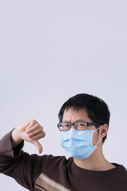 Retrato de un joven asiático, diciendo no a la infección por coronavirus con el uso de la máscara médica quirúrgica azul de la cara aislada en el fondo blanco, de cerca, de cerca
. - Foto, Imagen