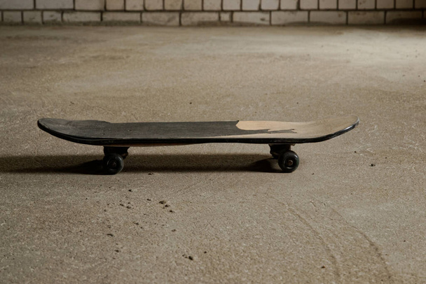 старый потрепанный скейтборд на бетонном полу в гараже. спортивная концепция. макро
 - Фото, изображение