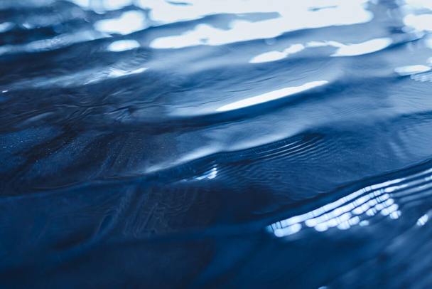 Крупный план спокойной поверхности воды с волнами темно-синего цвета. Модный свежий абстрактный фон природы. Цветовая концепция 2020
 - Фото, изображение