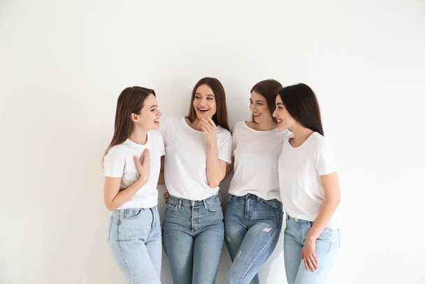Beautiful young ladies in jeans and white t-shirts on light background. Woman's Day - Photo, Image