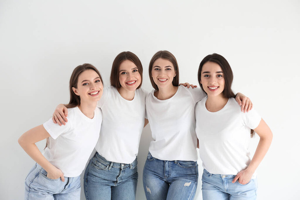 Beautiful young ladies in jeans and white t-shirts on light background. Woman's Day - Foto, immagini