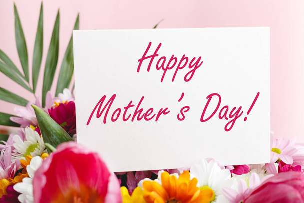 Happy Mothers Day text on gift card in flower bouquet on pink background. Greeting card for Mom. Flower delivery, Congratulations card in flowers for women. Greeting card in pink tulips. - Φωτογραφία, εικόνα