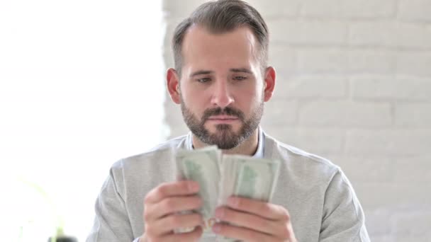 Portrait of Focused Young Man Counting Dollars - Materiał filmowy, wideo