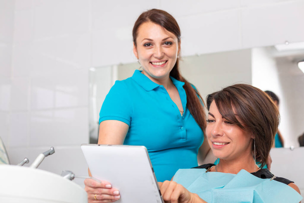 Retrato de un dentista discutiendo un plan de tratamiento con un paciente en una tableta
 - Foto, Imagen