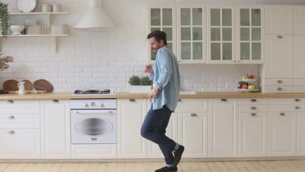 Full length overjoyed young funky guy funny dancing in kitchen. - Video