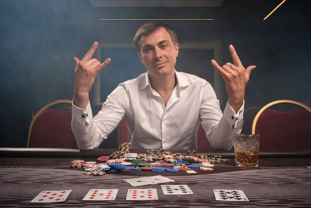 ハンサムな感情的な男はポーカーをプレイしているカジノのテーブルに座って. - 写真・画像