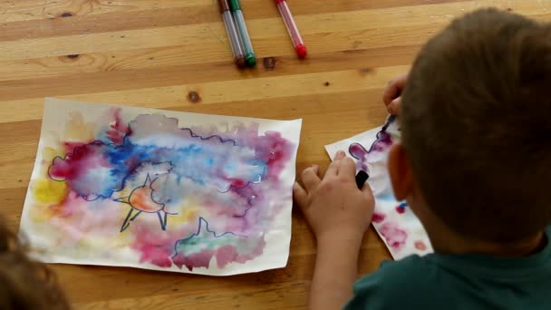 A preschooler boy enthusiastically draws in visual arts lessons in educational lessons for children. Drawing at the table above back shot. Creative education - Footage, Video