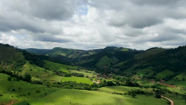 Luchtfoto van groene tropische berg en kleine vallei tijdens bewolkte dag - Video