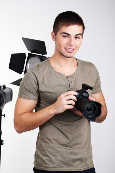 Handsome photographer with camera, on photo studio background - Zdjęcie, obraz