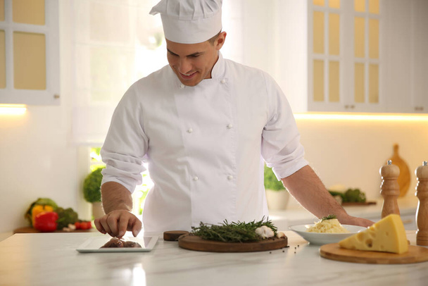 Chef with tablet cooking at table in kitchen - Foto, Imagen