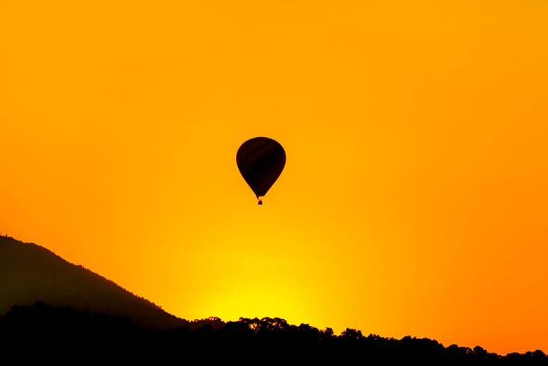 Il sole nascente al mattino e mongolfiera volare ovre montagna con sorprendente colore giallo e arancione
 - Foto, immagini