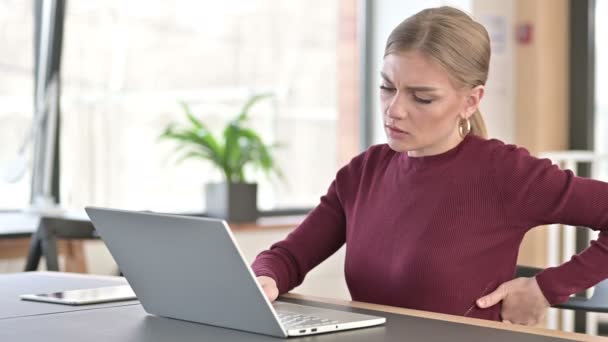 Νεαρή γυναίκα με πόνο στην πλάτη χρησιμοποιώντας Laptop στο γραφείο - Πλάνα, βίντεο
