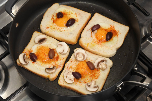 Above view of four fried eggs in toast bread slices fried in a frying pan - Photo, Image