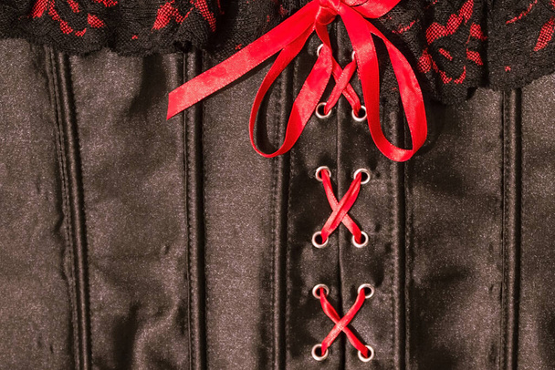 A satin corset with a red ribbon. Sexy underwear. Bed linen, secret defect. Desired, inviting woman. - Photo, Image
